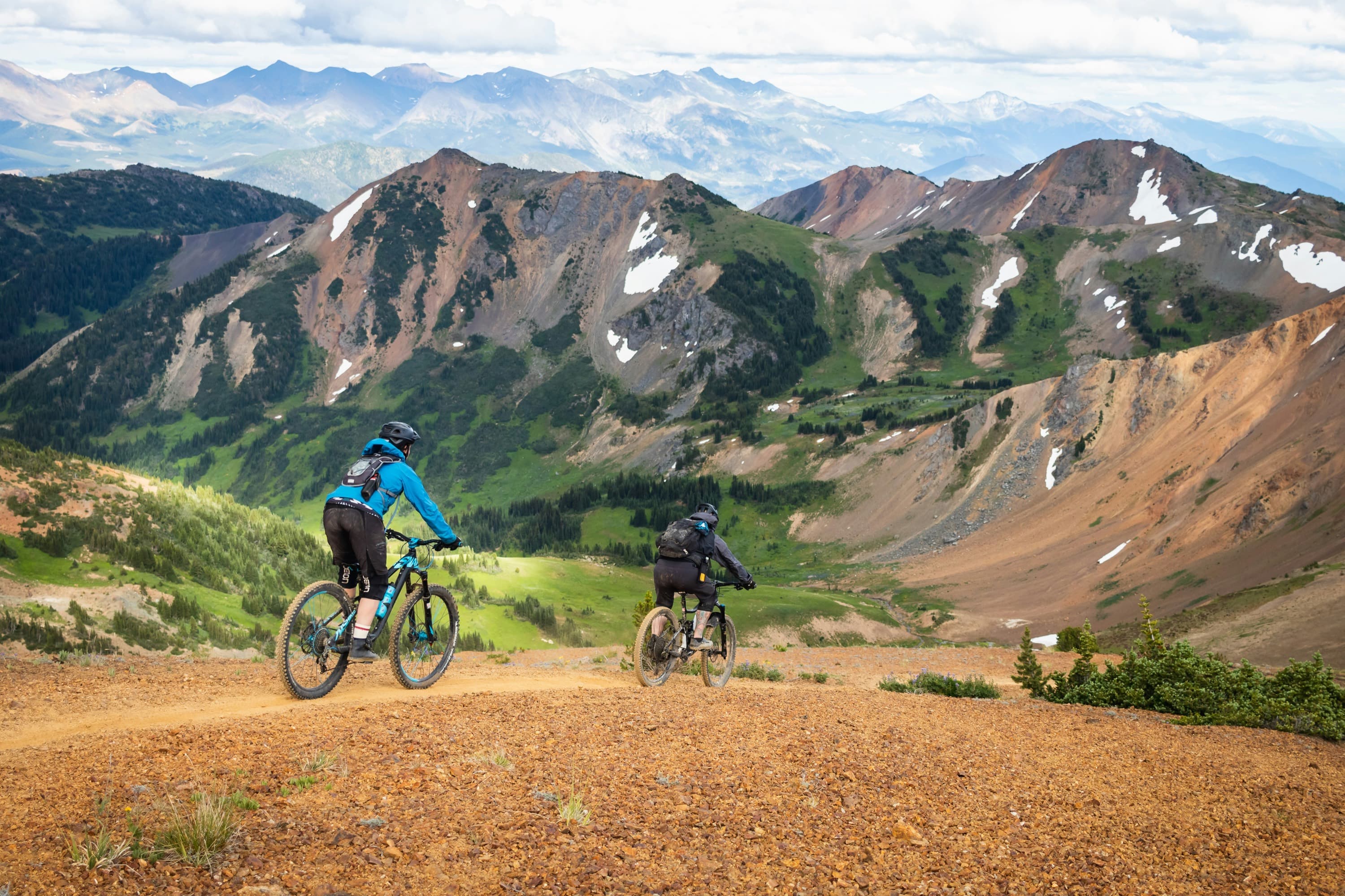 Riders on a gravel trail with open country beyond.