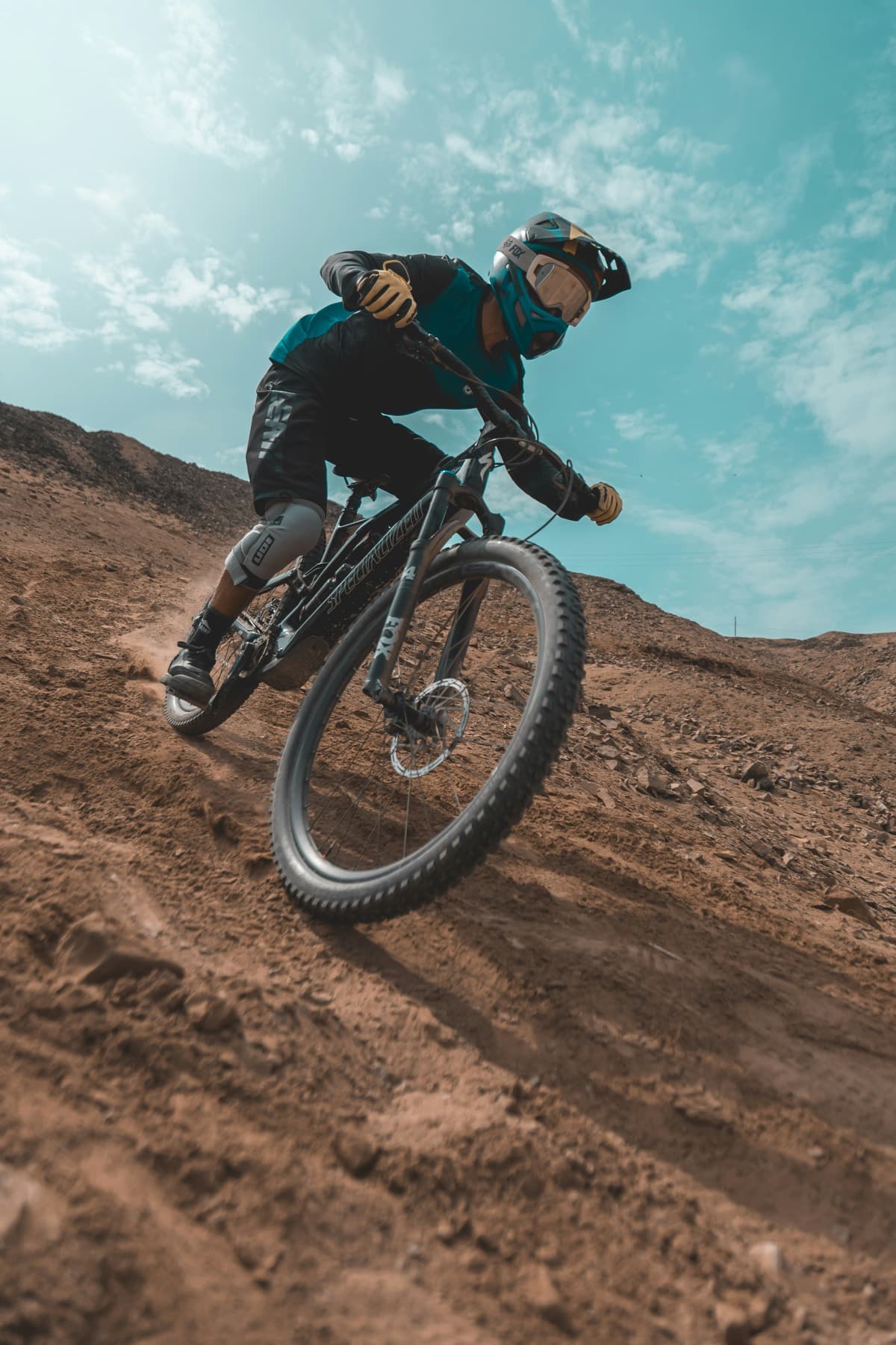 A rider carving down a dry, open hillside under a wide sky.